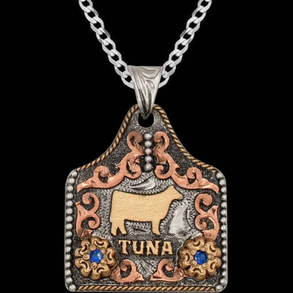 "Our Tuna Cow Tag Necklace is crafted on a German Silver base with copper hand-engraved scrollwork, Jeweler's Bronze logo and flowers with cubic zirconias of your choice. We finished the design of this cow tag with a rope and bead edge combination an